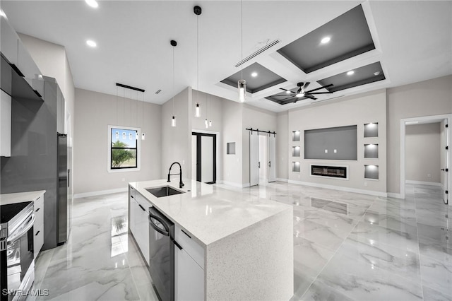 kitchen with an island with sink, a barn door, modern cabinets, and pendant lighting