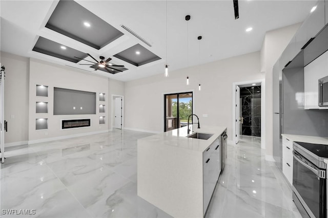 kitchen with marble finish floor, decorative light fixtures, appliances with stainless steel finishes, a kitchen island with sink, and a sink