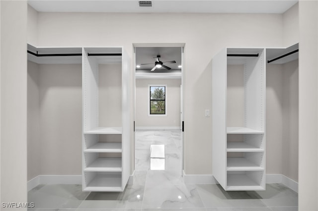 walk in closet featuring a barn door, tile patterned flooring, and ceiling fan