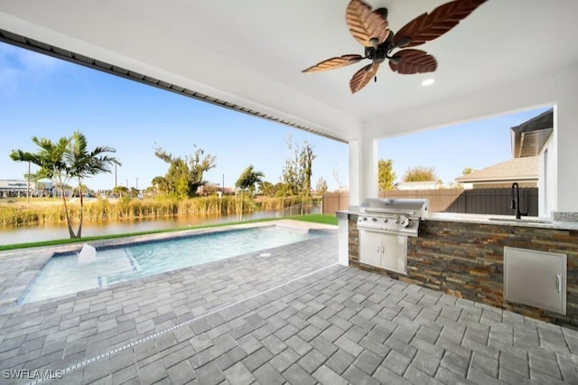 view of patio / terrace with a fenced in pool, ceiling fan, an outdoor kitchen, grilling area, and sink