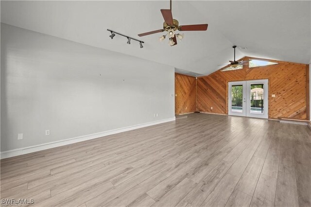 unfurnished living room with light hardwood / wood-style floors, vaulted ceiling, french doors, and ceiling fan