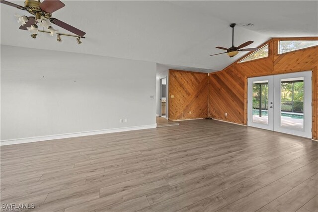 unfurnished living room with ceiling fan, vaulted ceiling, french doors, and light wood-type flooring