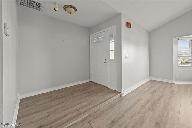 foyer entrance with light hardwood / wood-style flooring and vaulted ceiling