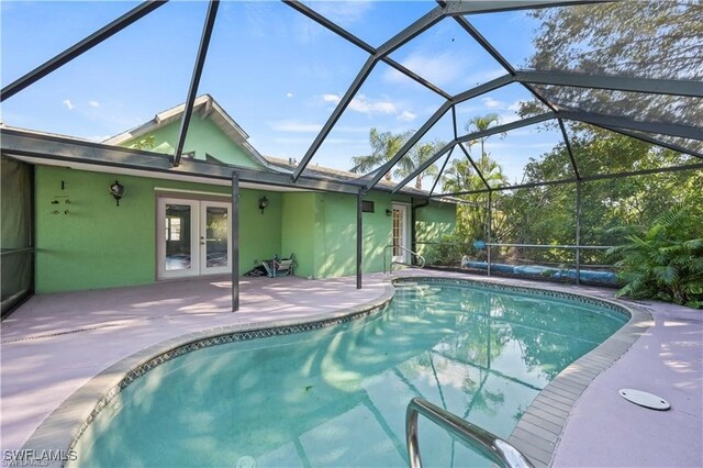 view of pool featuring glass enclosure, a patio, and french doors