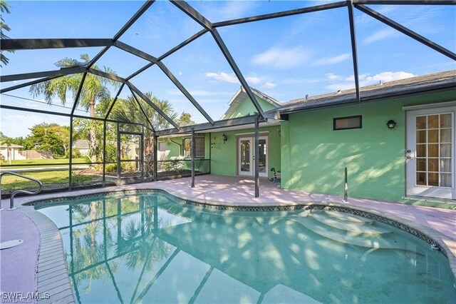 view of swimming pool featuring glass enclosure, french doors, and a patio