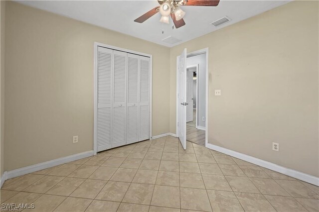 unfurnished bedroom featuring ceiling fan, light tile patterned flooring, and a closet