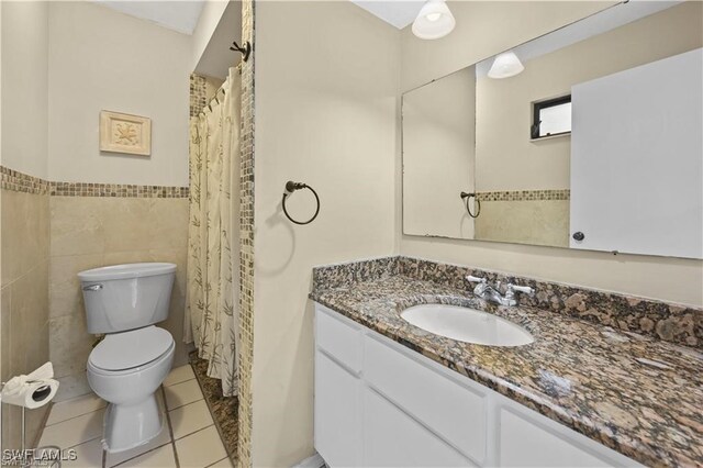 bathroom with tile walls, tile patterned flooring, vanity, and toilet