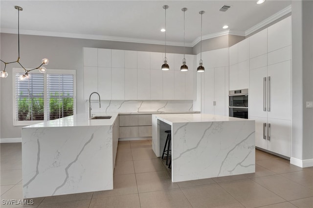 kitchen with sink, ornamental molding, light stone countertops, a kitchen island, and pendant lighting