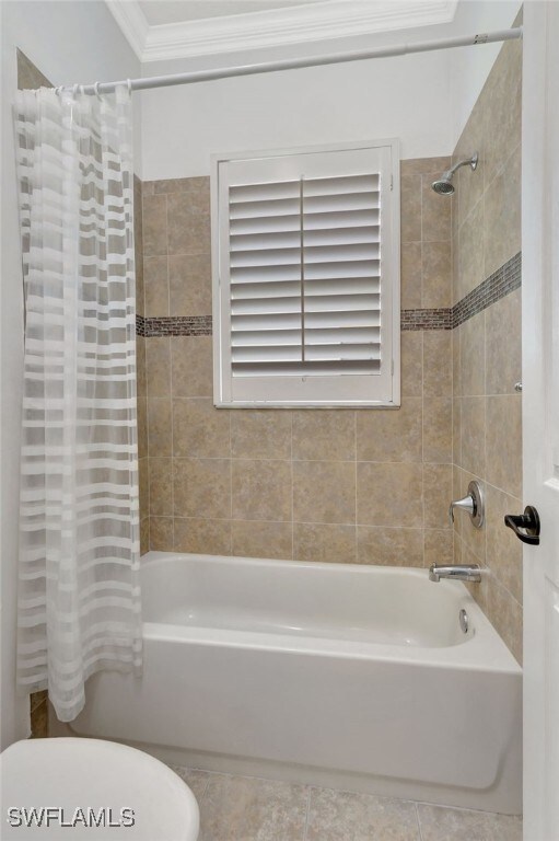 bathroom with shower / bath combination with curtain, toilet, ornamental molding, and tile patterned floors