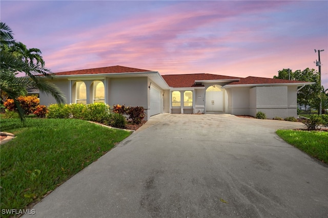 view of front of house featuring concrete driveway, a yard, an attached garage, and stucco siding