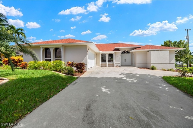 view of front of home with driveway, a front yard, an attached garage, and stucco siding