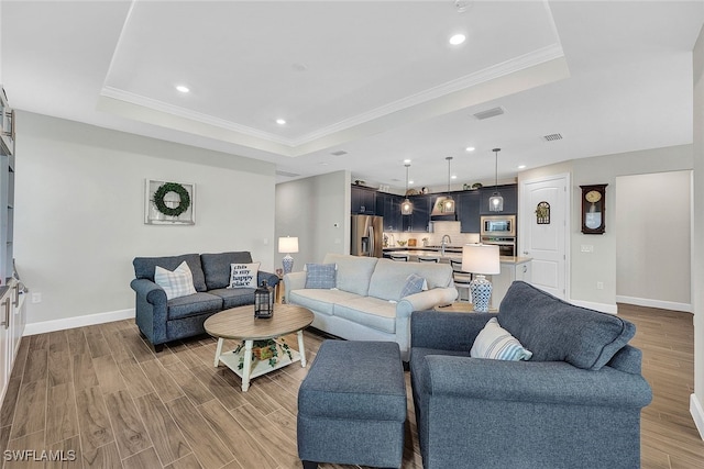 living room with ornamental molding, a tray ceiling, and hardwood / wood-style floors