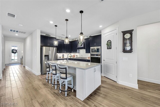 kitchen with light countertops, light wood-type flooring, visible vents, and stainless steel appliances