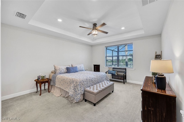 bedroom featuring light colored carpet, a raised ceiling, and ceiling fan