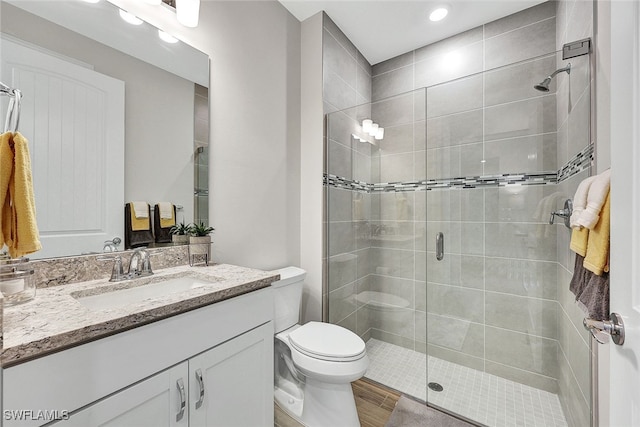 bathroom featuring vanity, a shower with shower door, and toilet