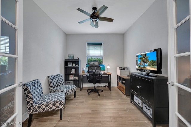 office area with baseboards, light wood-style floors, and ceiling fan