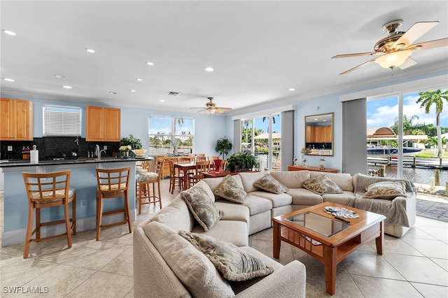 living room with light tile patterned flooring, ceiling fan, a water view, and crown molding