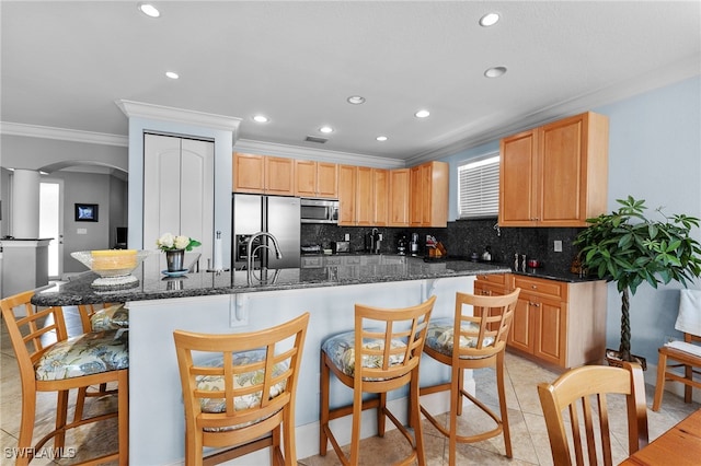 kitchen with decorative backsplash, a kitchen island, dark stone countertops, light tile patterned flooring, and stainless steel appliances