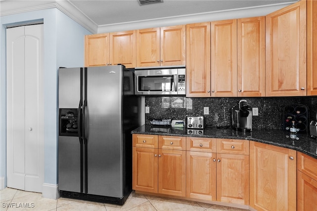 kitchen with dark stone counters, backsplash, crown molding, light tile patterned flooring, and stainless steel appliances