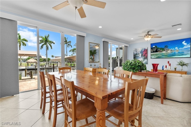 tiled dining space featuring ceiling fan and crown molding