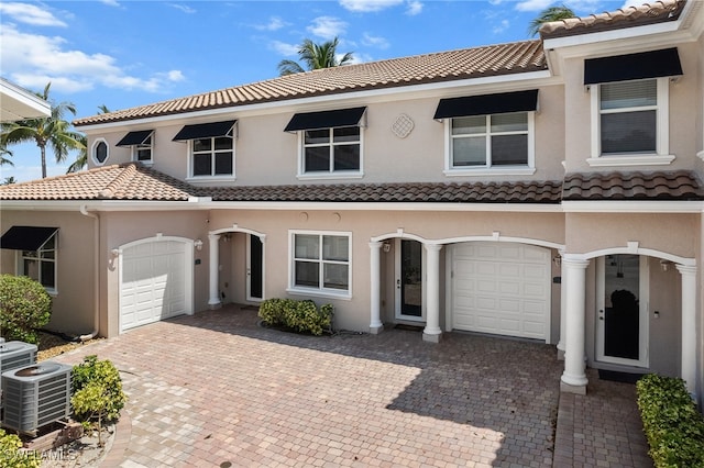 mediterranean / spanish-style home featuring central air condition unit and a garage