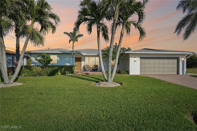 ranch-style house featuring a garage and a lawn