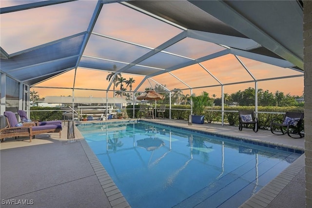 pool at dusk with a patio and glass enclosure