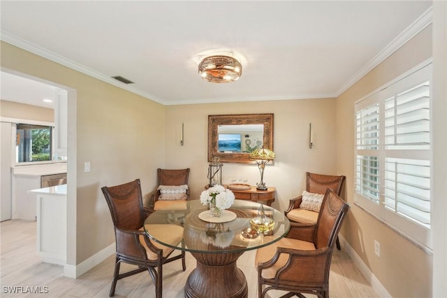 dining area with ornamental molding and light hardwood / wood-style flooring