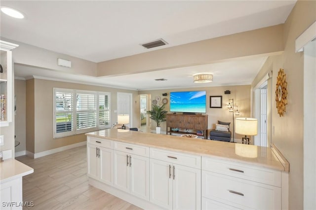 kitchen with crown molding, light stone counters, light hardwood / wood-style flooring, and white cabinets