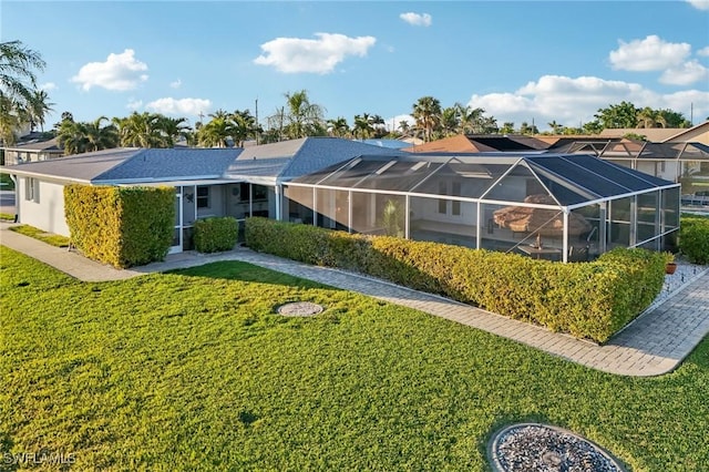 rear view of property with a yard and glass enclosure