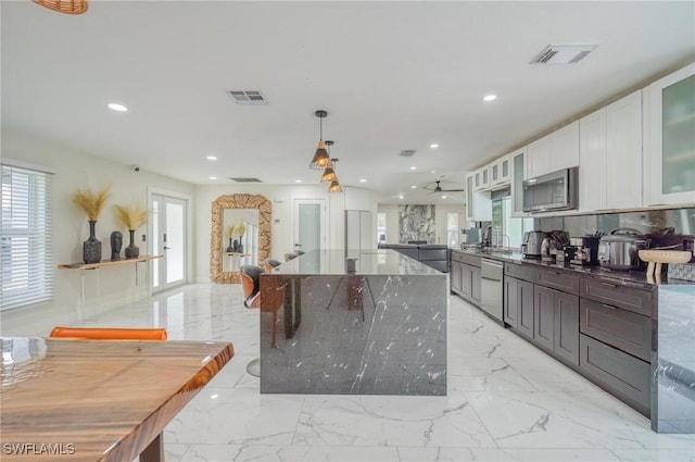 kitchen with plenty of natural light, dark stone countertops, white cabinetry, and appliances with stainless steel finishes