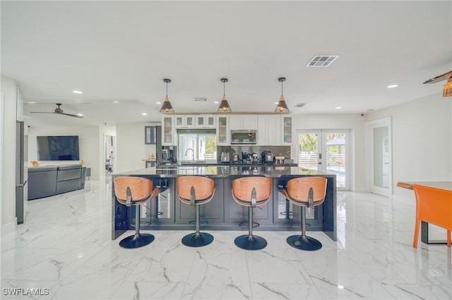 kitchen featuring a breakfast bar, stainless steel appliances, white cabinetry, and hanging light fixtures