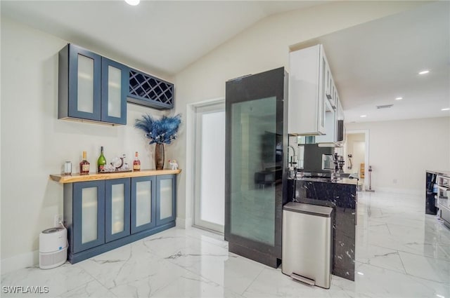 kitchen with wood counters, blue cabinets, and vaulted ceiling