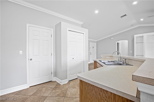 kitchen featuring light tile patterned flooring, sink, ornamental molding, and lofted ceiling