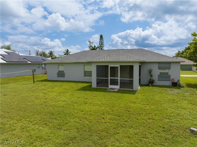 rear view of property with a sunroom, solar panels, and a lawn