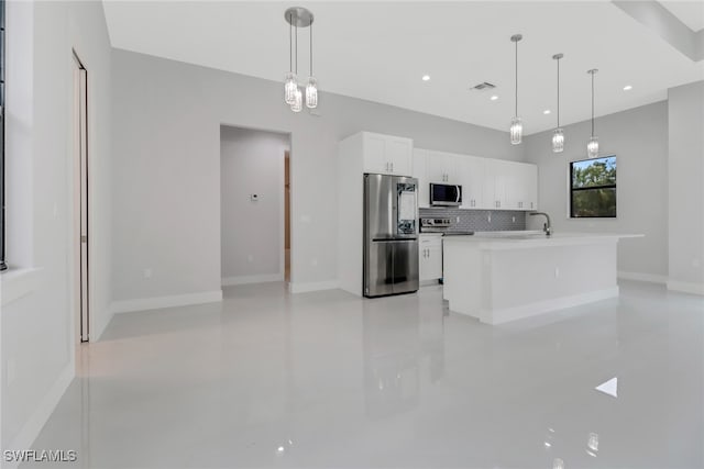 kitchen with stainless steel appliances, decorative backsplash, an island with sink, white cabinets, and hanging light fixtures