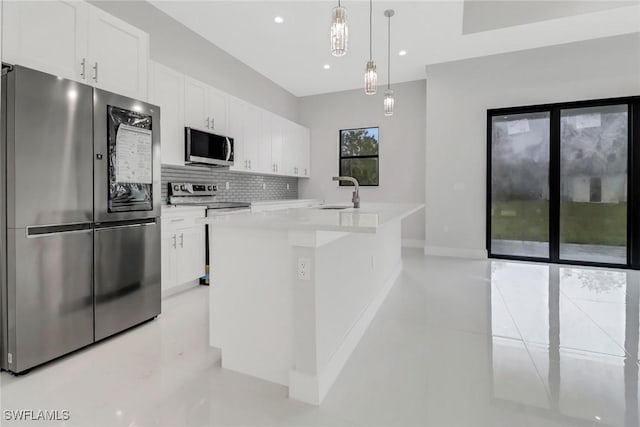 kitchen with a center island with sink, hanging light fixtures, stainless steel appliances, white cabinets, and sink