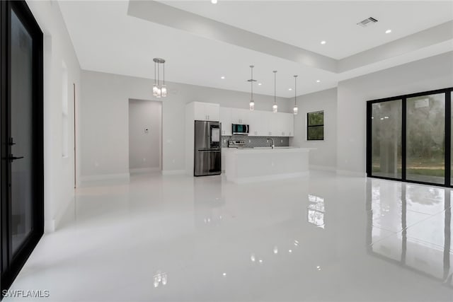 unfurnished living room featuring sink and a raised ceiling