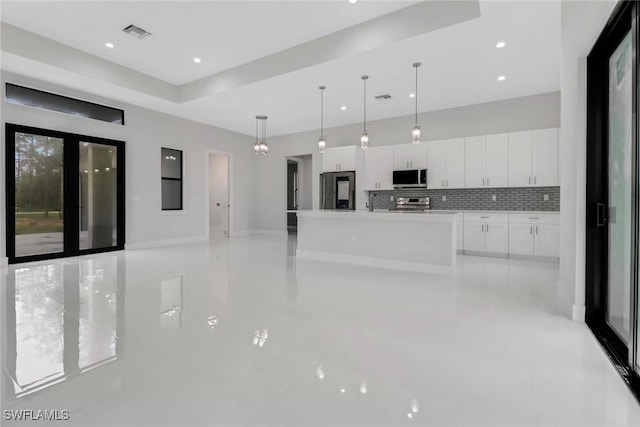 kitchen with a center island, stainless steel appliances, decorative light fixtures, tasteful backsplash, and white cabinets