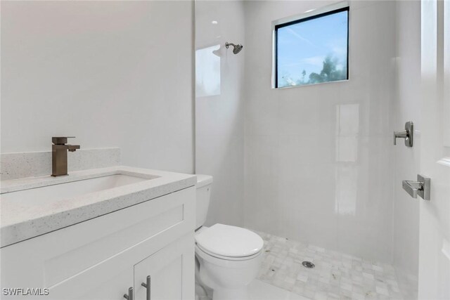 bathroom featuring toilet, a tile shower, and vanity