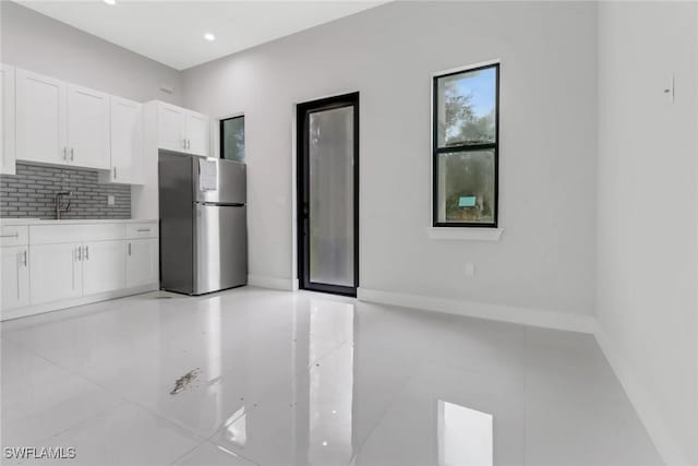 kitchen featuring sink, white cabinetry, stainless steel fridge, and backsplash