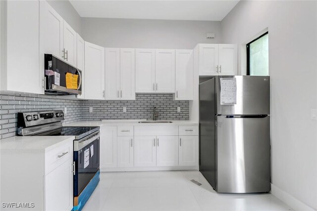 kitchen with backsplash, stainless steel appliances, white cabinetry, sink, and light tile patterned floors