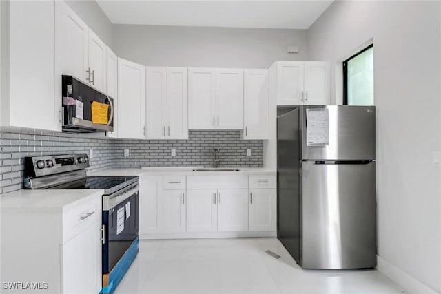 kitchen featuring stainless steel appliances, white cabinets, backsplash, light tile patterned floors, and sink