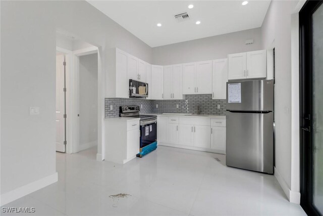 kitchen with light tile patterned flooring, stainless steel appliances, tasteful backsplash, and white cabinets