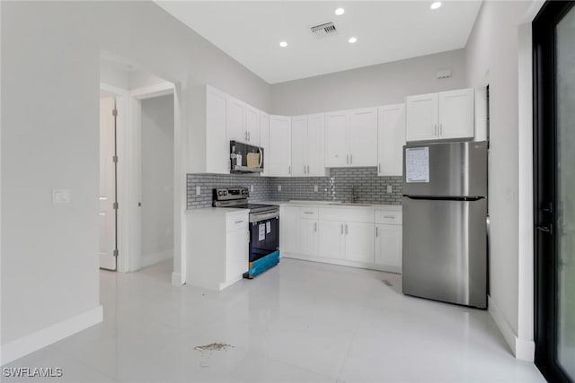 kitchen with appliances with stainless steel finishes, sink, tasteful backsplash, and white cabinets