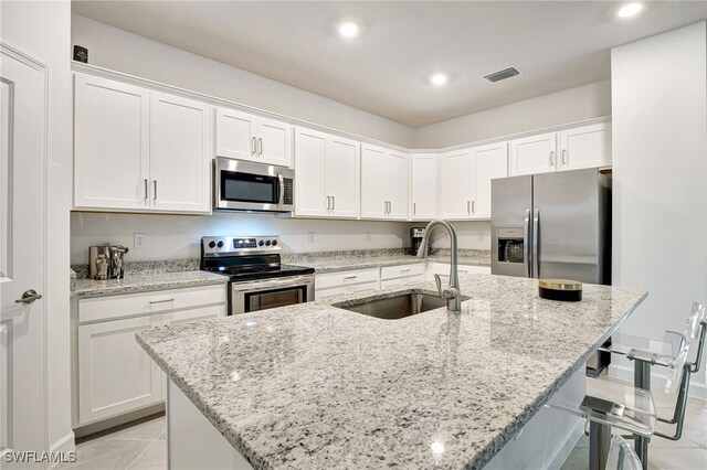 kitchen featuring stainless steel appliances, a center island with sink, and white cabinets