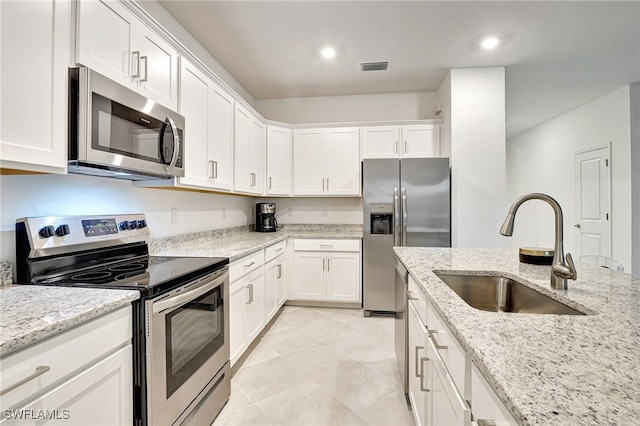 kitchen featuring stainless steel appliances, white cabinetry, light stone countertops, and sink