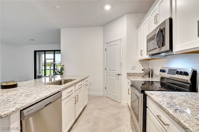 kitchen featuring appliances with stainless steel finishes, a sink, white cabinetry, and light stone countertops