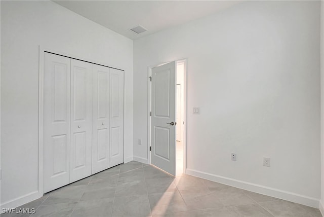 unfurnished bedroom with a closet, visible vents, baseboards, and light tile patterned floors