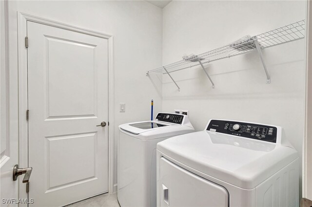 clothes washing area with independent washer and dryer and light tile patterned floors